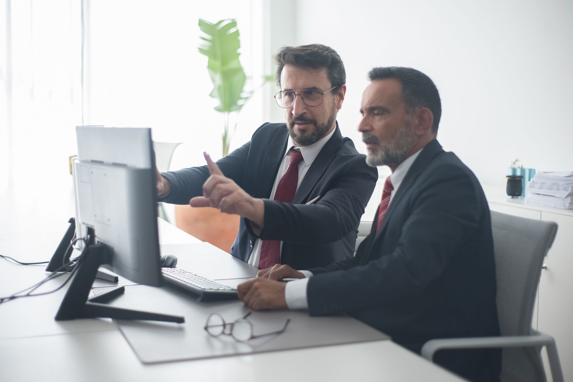 Dois profissionais diante de um monitor, um deles apontando para o projeto na tela